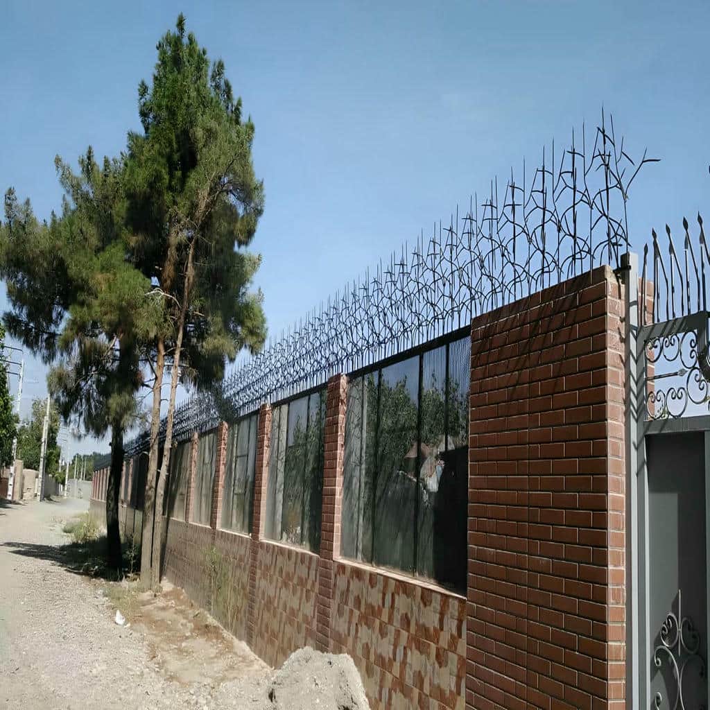 ردیف سرنیزه های فلزی بالای دیوار ورودی